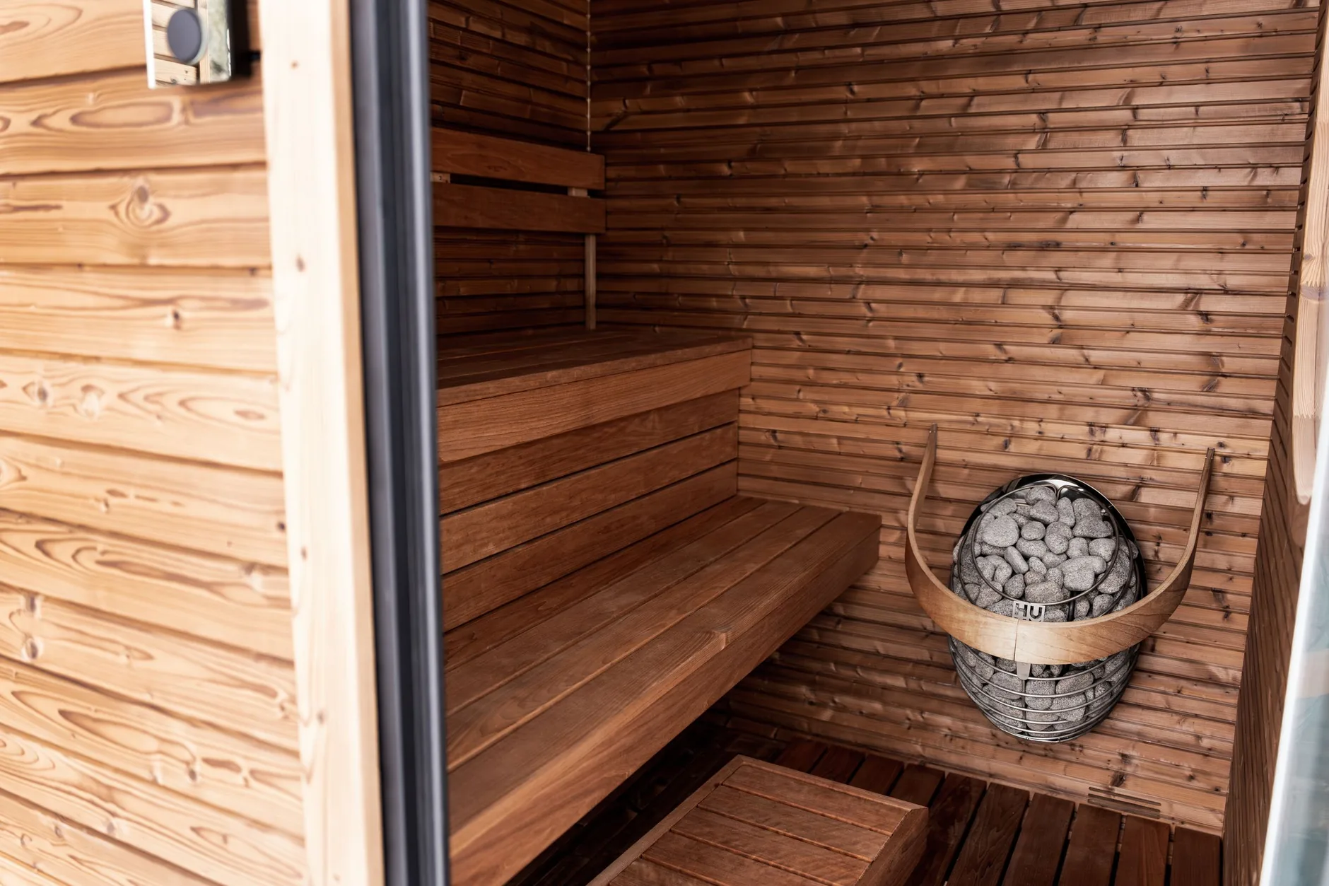 Valmis sauna ja pesuhuone lasiseinällä ja puisilla lauteilla